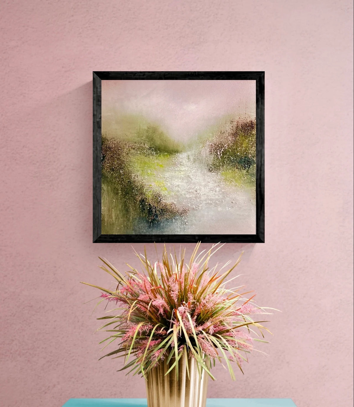 Ticked Pink by Gillian Lazanik, a framed textured landscape in soft pink, green, and earthy tones, displayed on a pink wall.