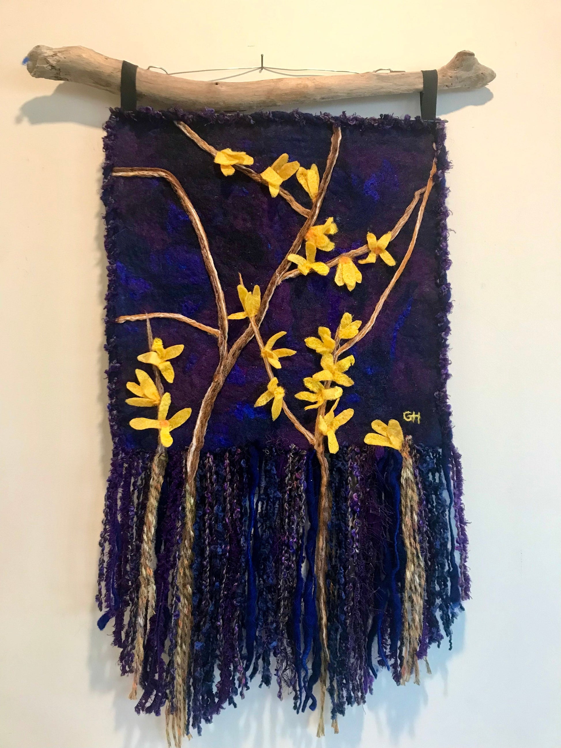 Forsythia - wet-felted fibre art wall hanging by Gail Heinze, 12x12 inches plus fringe, yellow forsythia blooms on deep purple background, hung from NS driftwood